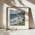 Framed artwork of a coastal landscape with a beach and ocean.