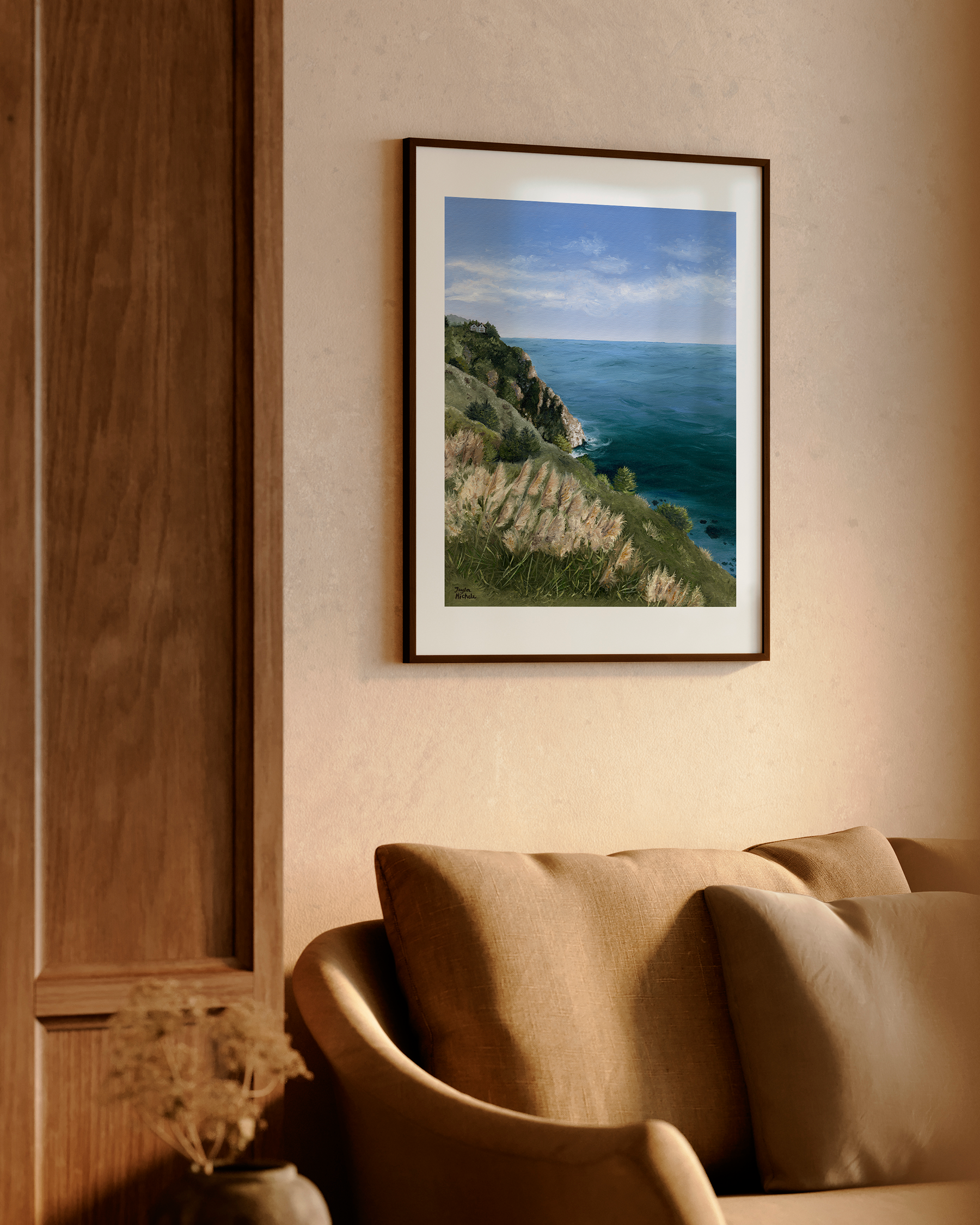 Framed artwork of a coastal scene on a wall above a sofa.