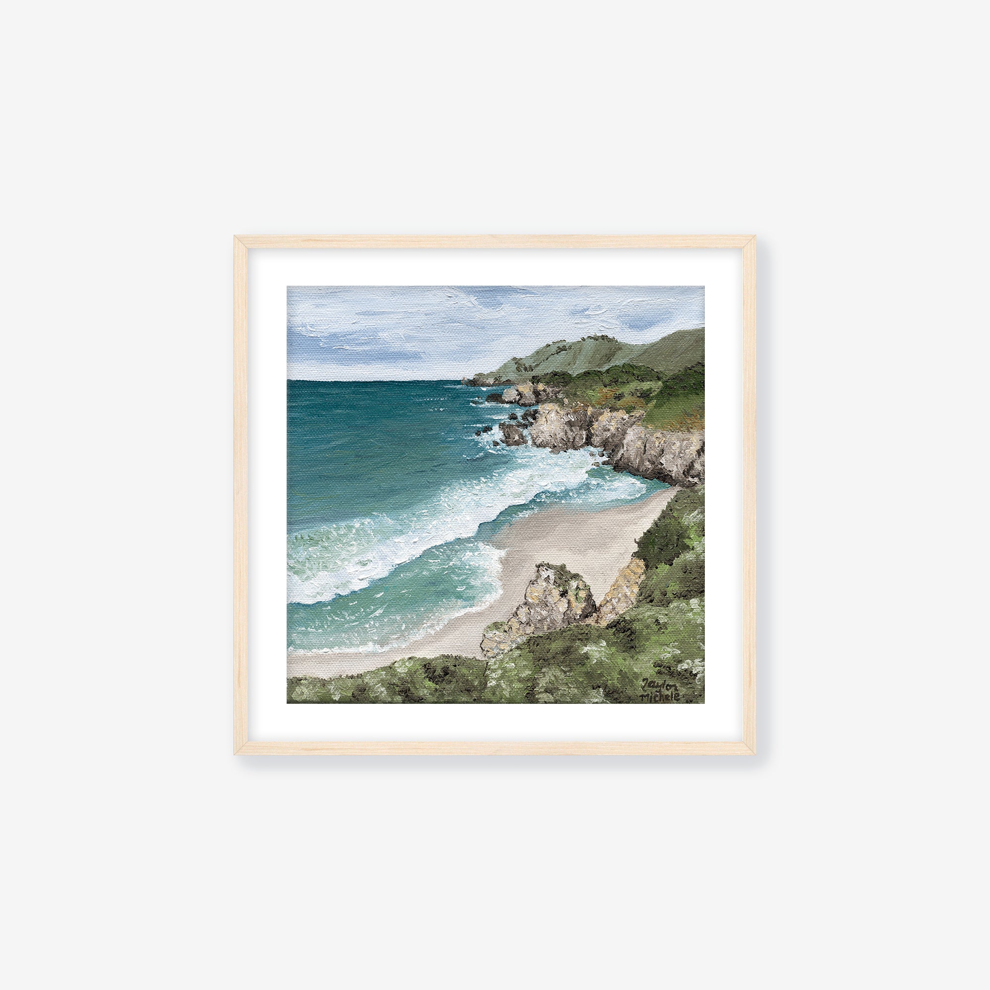 Framed artwork of a coastal landscape with ocean and beach. Maple frame