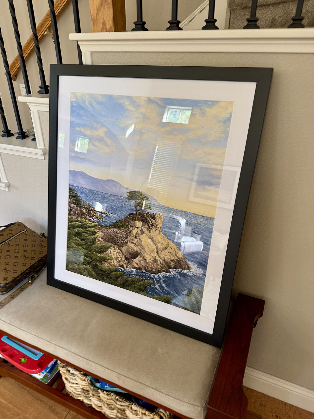 Framed artwork of a coastal scene on a staircase landing