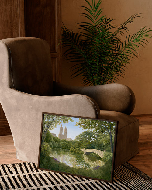 Framed artwork of a park scene on a coffee table next to a plush armchair.