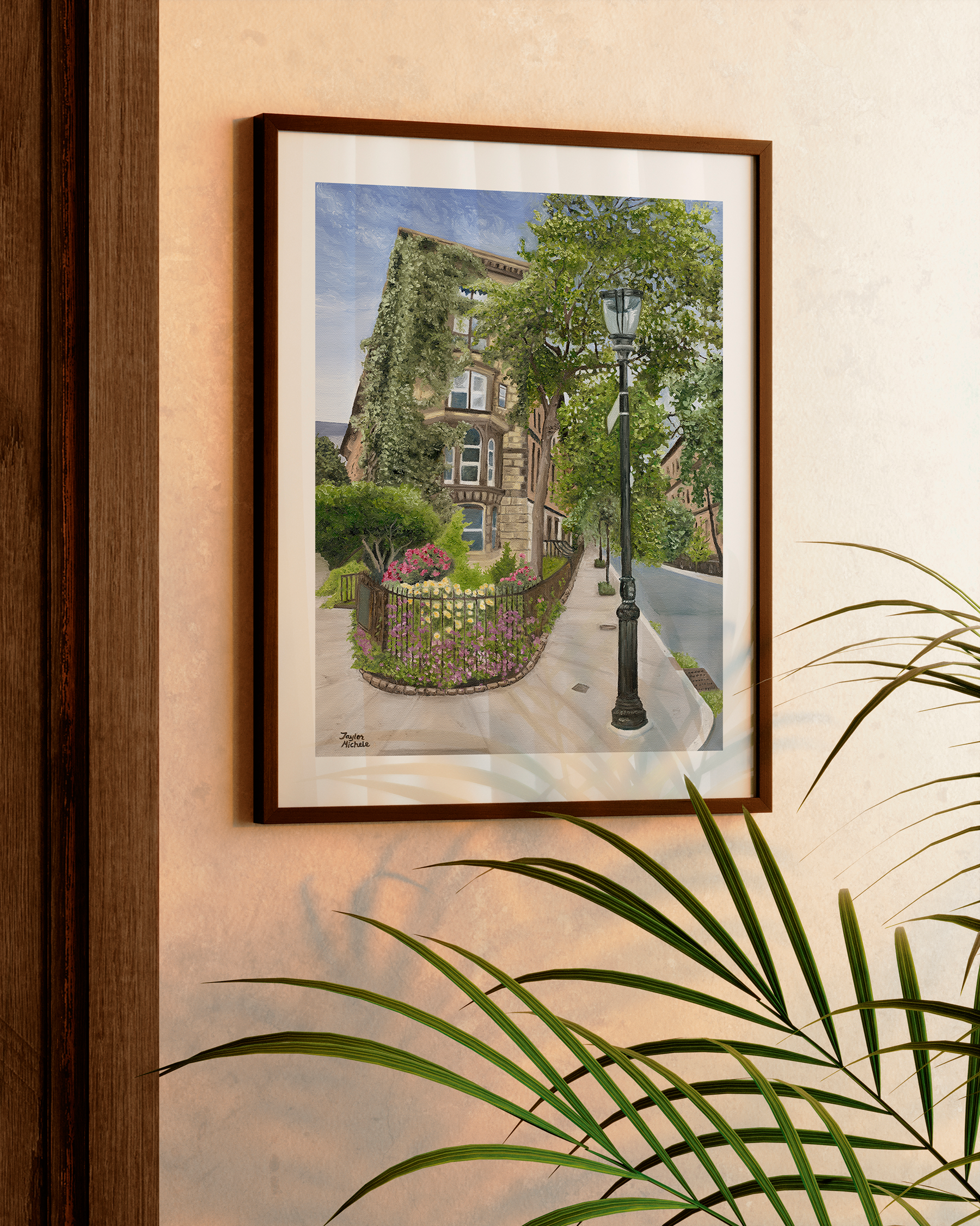 Framed artwork of a street scene with a building and lamp post on a wall.