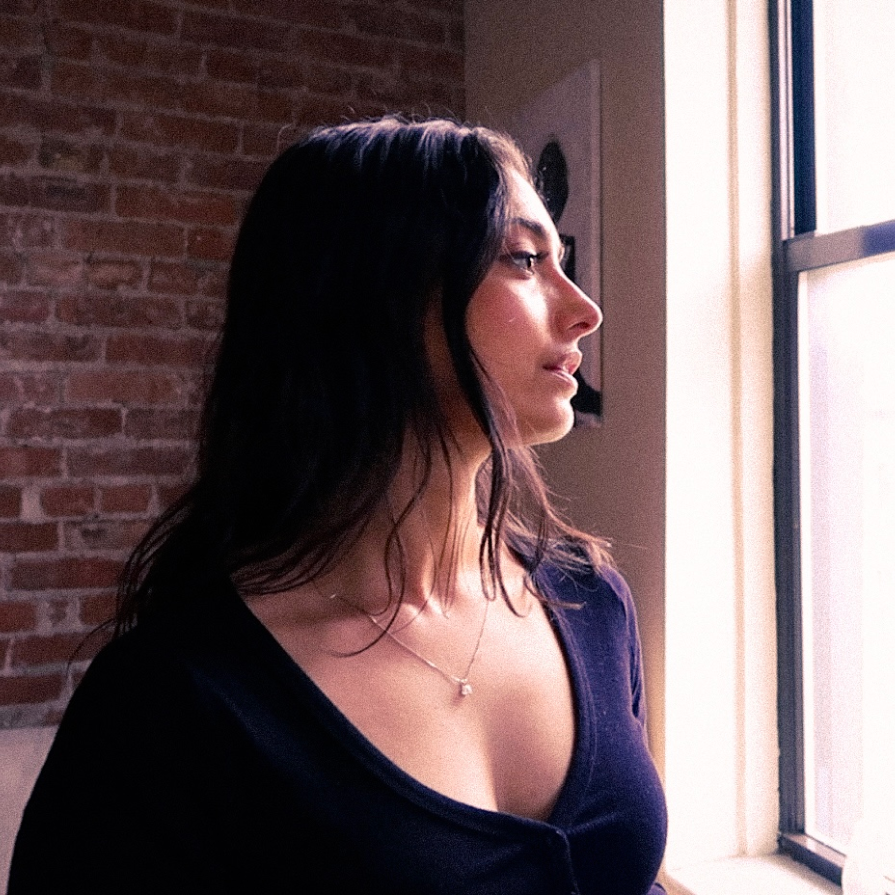 Woman standing by a window with a brick wall in the background