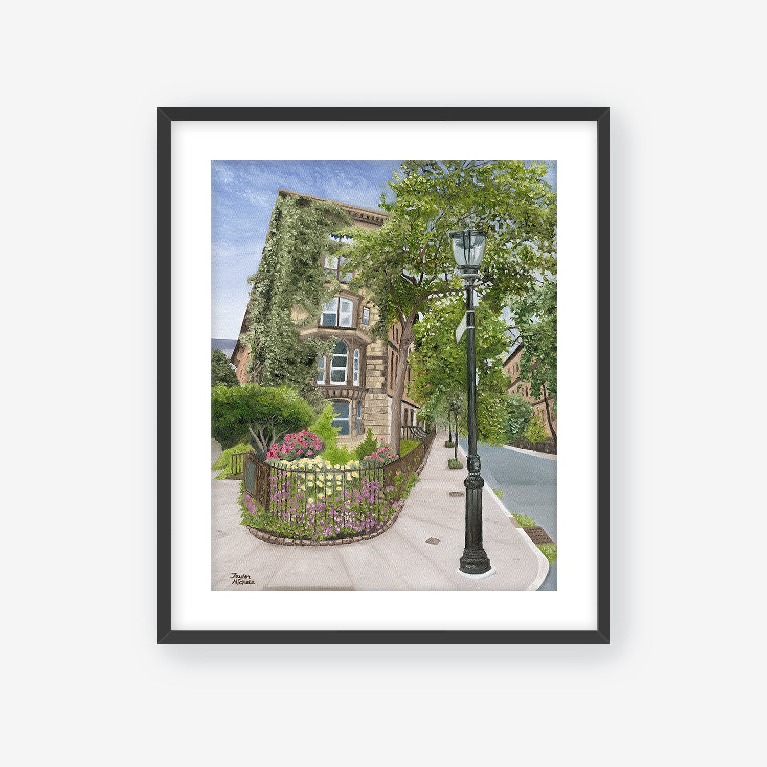 Framed artwork of a street scene with a lamp post, garden, and building. Black frame