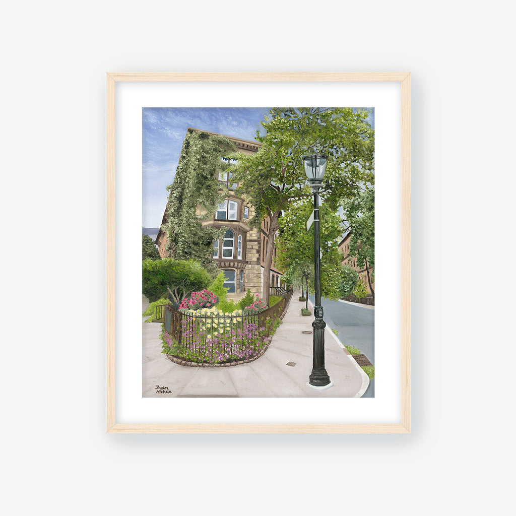 Framed artwork of a street scene with a lamp post, house, and garden. Maple Frame