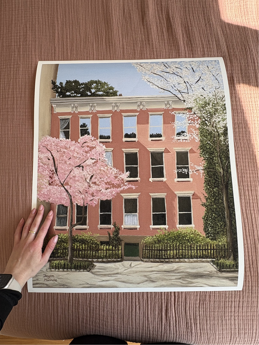 Art print of a pink building with cherry blossom trees on a earth tone pink fabric surface