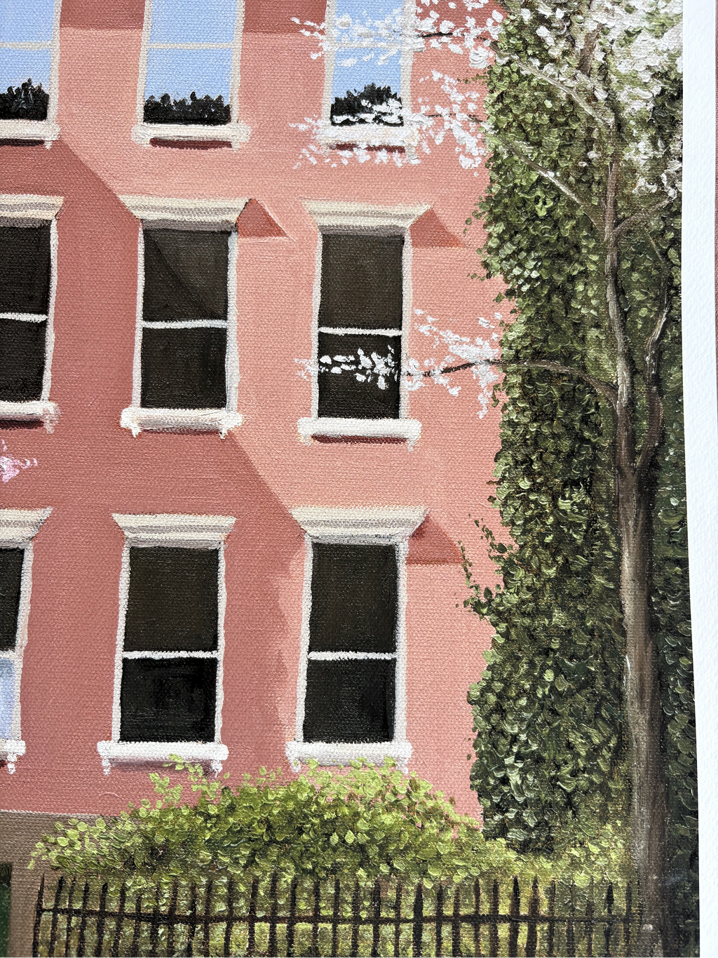 Close up shot of a fine art print of an oil painting of a pink building with windows and greenery