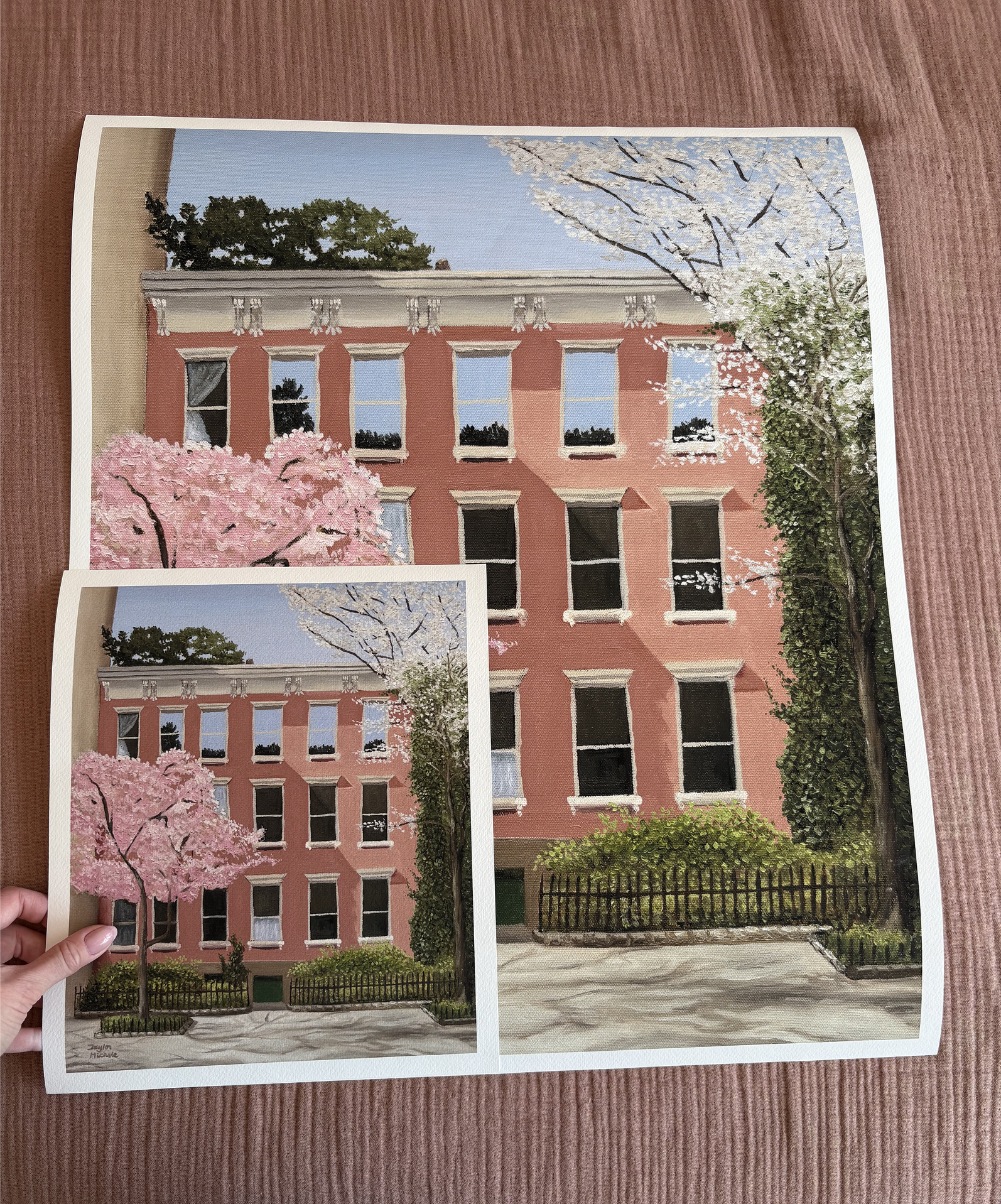 Two prints of a building with cherry blossoms on a wooden surface to show the difference in size