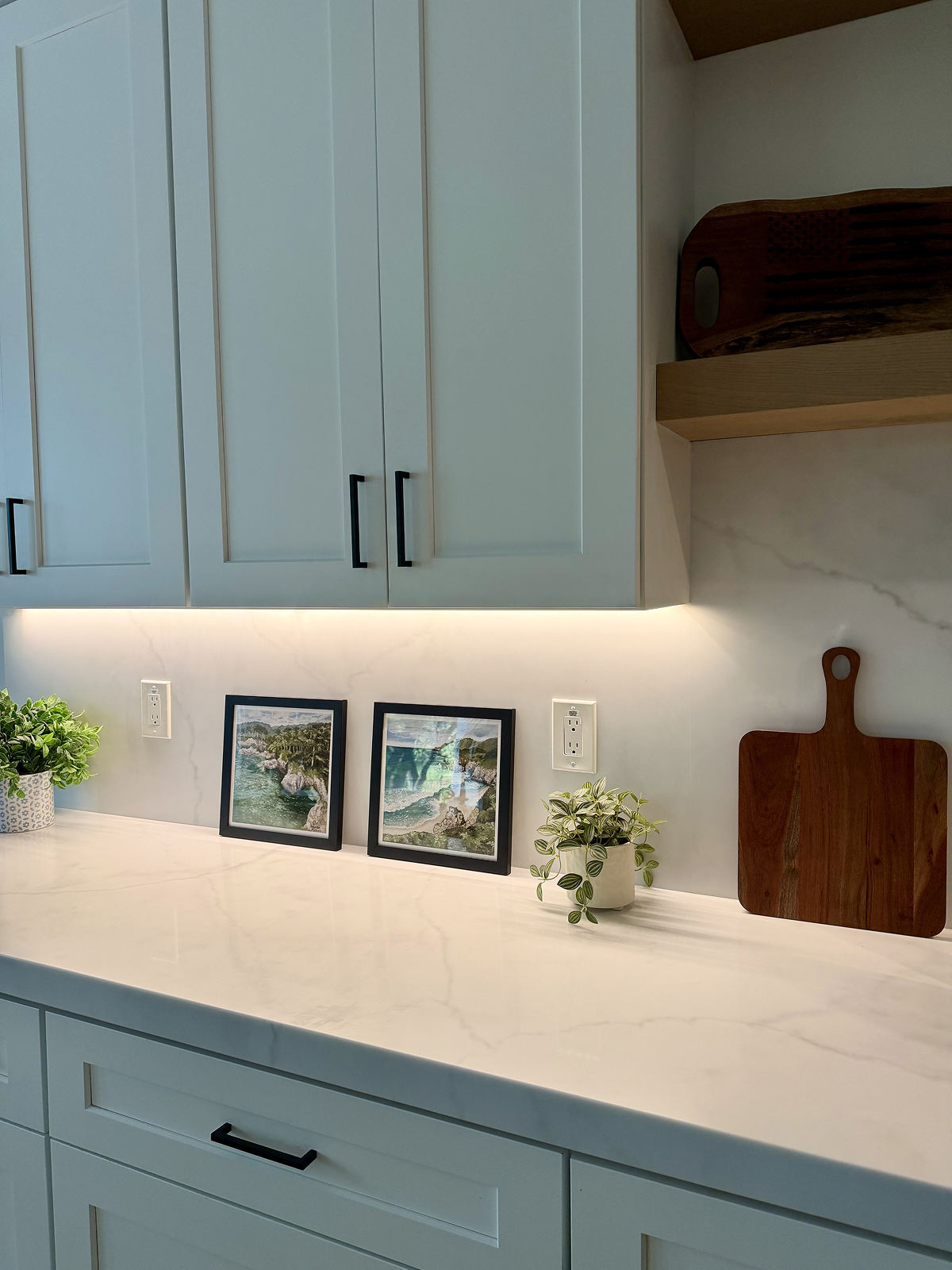 Modern kitchen with light blue cabinets, white countertops, and decorative elements.